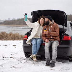 Couple sitted on car backside and enjoy the snow Weather