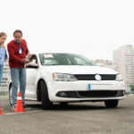 Instructor teaching student to drive white car.