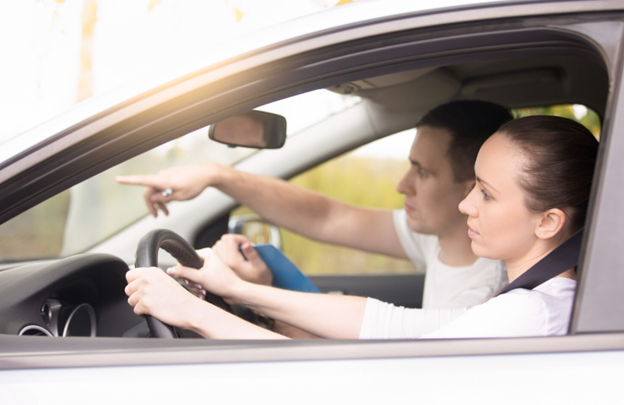 Man guiding woman in car driving lesson